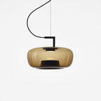 Wide amber glass Clérachic pendant with a black stem bracket and a smooth, rounded shade on a white backdrop.