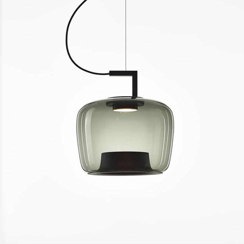 Squat grey-green glass Clérachic pendant with ribbed edges and a black base, lit softly on a white backdrop.