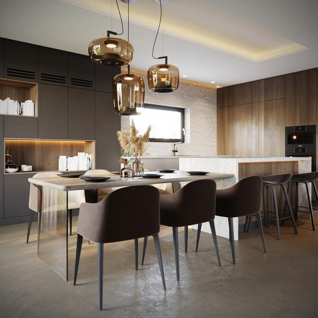 Three amber glass Clérachic pendants hang above a long dining table in a dark-cabinet kitchen with warm wood panels.