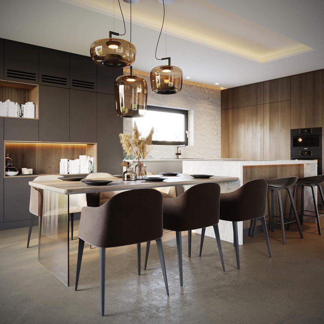 Three amber glass Clérachic pendants hang above a long dining table in a dark-cabinet kitchen with warm wood panels.
