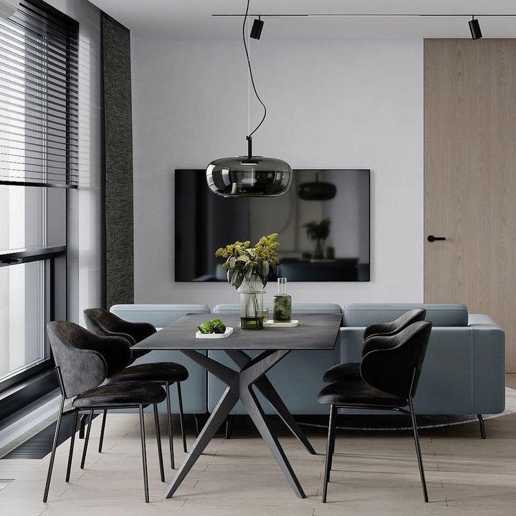 Smoke grey glass Clérachic pendant above a dark dining table with black chairs, in front of a wall-mounted TV.
