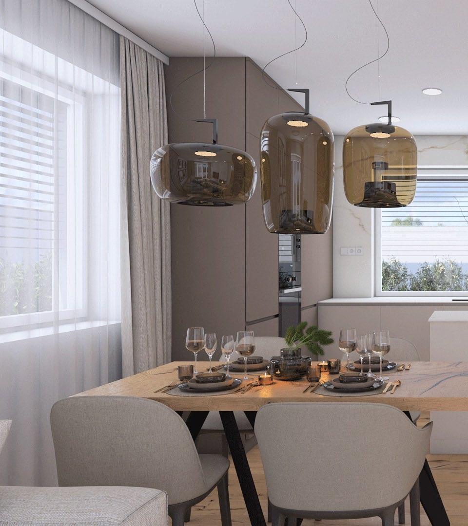 Three amber-brown Clérachic pendants hang above a wooden dining table with grey chairs, beside a curtained window.