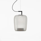 Tall pale grey glass Clérachic pendant with a black bracket, the inner base faintly visible, on a white backdrop.