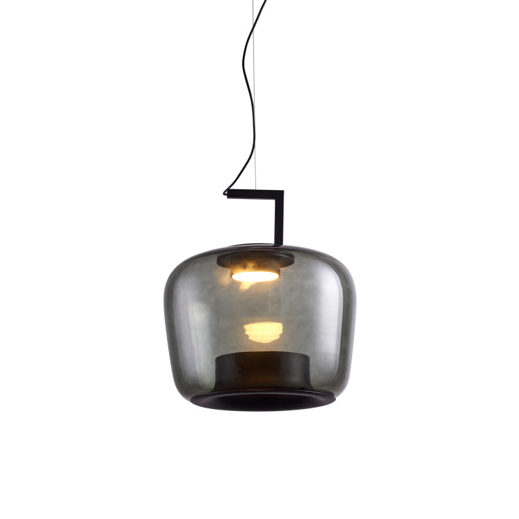 Squat smoke grey glass Clérachic pendant with the bulb glowing warmly inside, on a white backdrop.