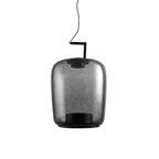 Tall smoke grey glass Clérachic pendant, unlit, with a black bracket and a dark ring at its base.