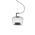 Squat clear glass Clérachic pendant with a black bracket and a dark base, hanging on a curved cord on white.