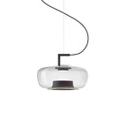 Wide clear glass Clérachic pendant with a black bracket and a dark base ring on a curved cord, on white.