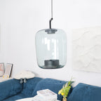 Tall grey-green glass Clérachic pendant above a blue velvet sofa, with a framed print and a plaster wall panel behind.
