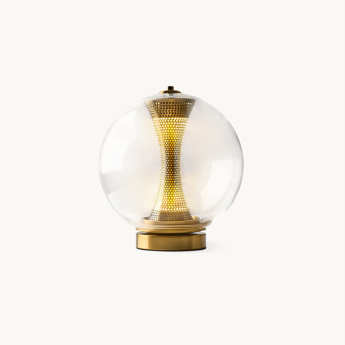 This Clérachic glass sphere table lamp on a plain white backdrop, a glowing woven brass column inside, on a gold base.