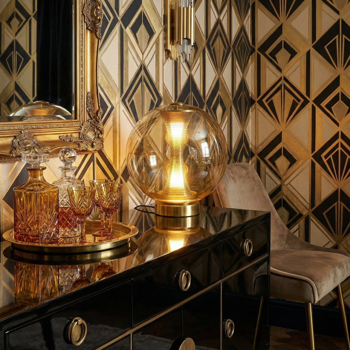 This Clérachic lamp's cognac glass glows on a black lacquer cabinet in front of art deco wallpaper, with cut-glass decanters.