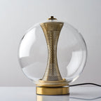 Unlit Clérachic clear-glass sphere lamp front on, the brass column pale and perforated above a brushed gold base.
