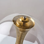 Close view of the flared, perforated top of the brass column and its cap inside the glass sphere of this Clérachic lamp.