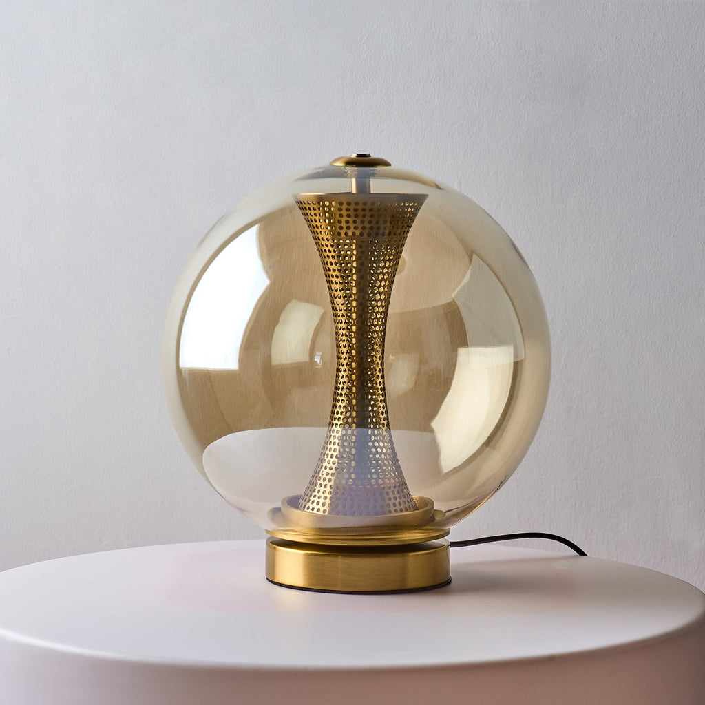 Compact Clérachic cognac sphere lamp on a pale round stand, unlit, with the brass column visible through the tinted glass.