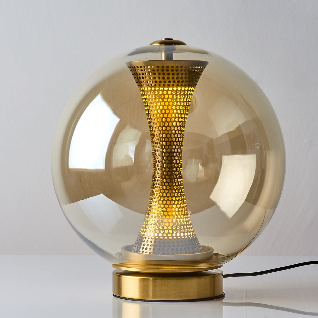 Front view of this Clérachic cognac sphere lamp, lit, with a warm glow in the brass column above its brushed gold base.
