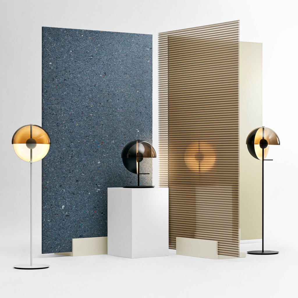 Floor and table lamps from Clérachic in the same range stand before panels of blue speckled stone and ribbed timber on a white floor.