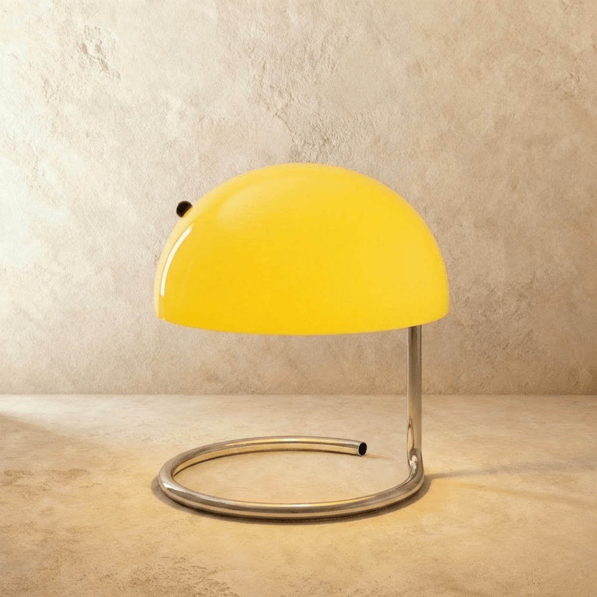 Clérachic's yellow dome table lamp glows atop a spiral chrome base against a warm plaster wall.