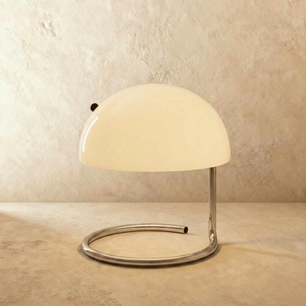 Clérachic's white dome-shade table lamp sits on its chrome spiral base against a plaster backdrop.