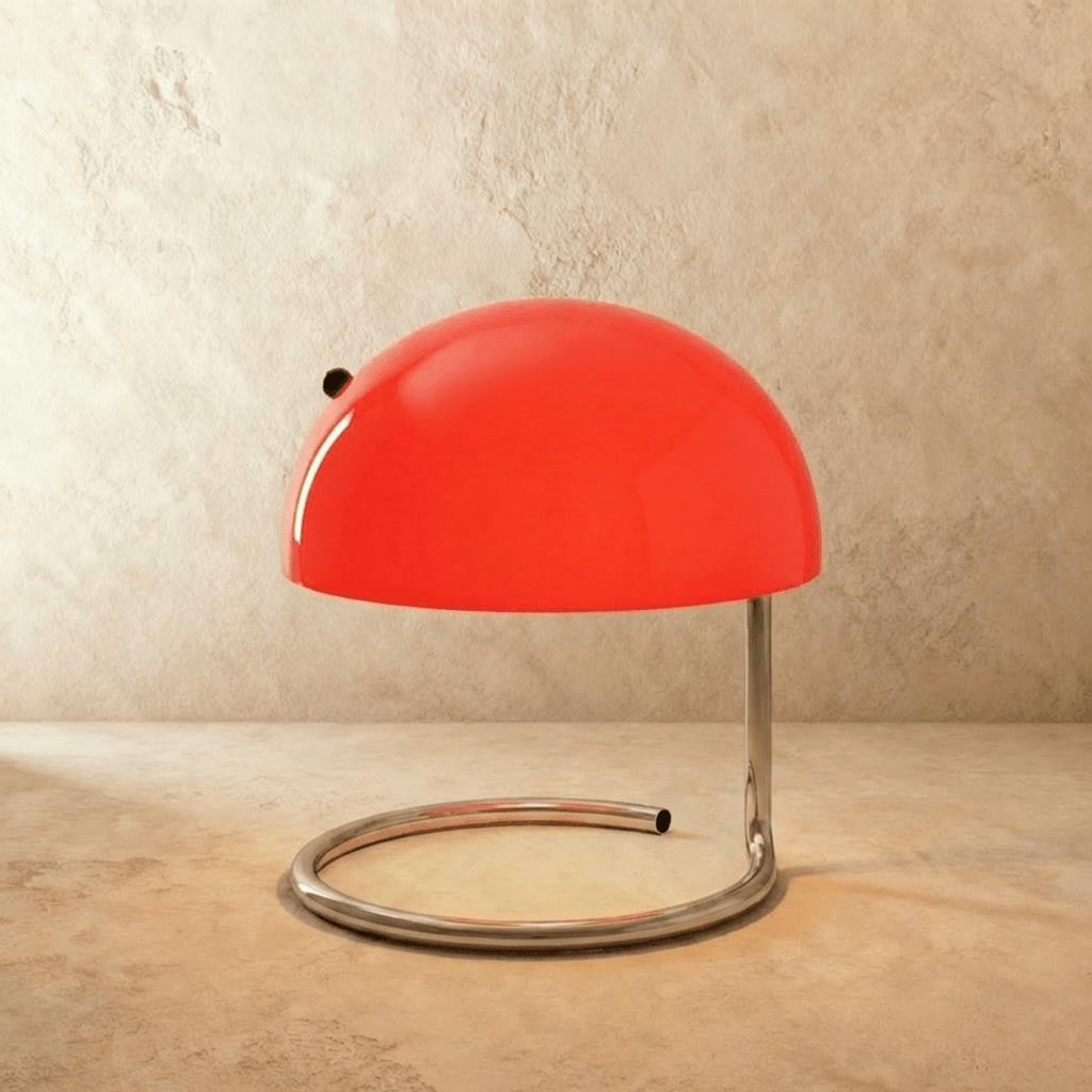 Clérachic's red glass dome table lamp stands on a coiled chrome base against a warm textured wall.