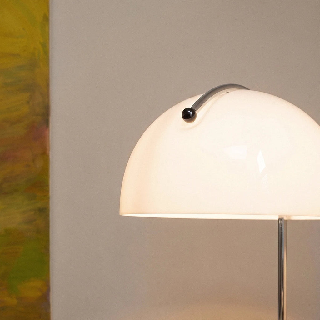 Close-up of the Clérachic white glass dome shade shows its curved handle and glowing chrome stem.