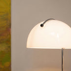 Close-up of the Clérachic white glass dome shade shows its curved handle and glowing chrome stem.