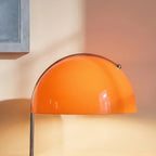 Close-up of the Clérachic orange glass dome shade catches warm light beside a pale blue picture frame.