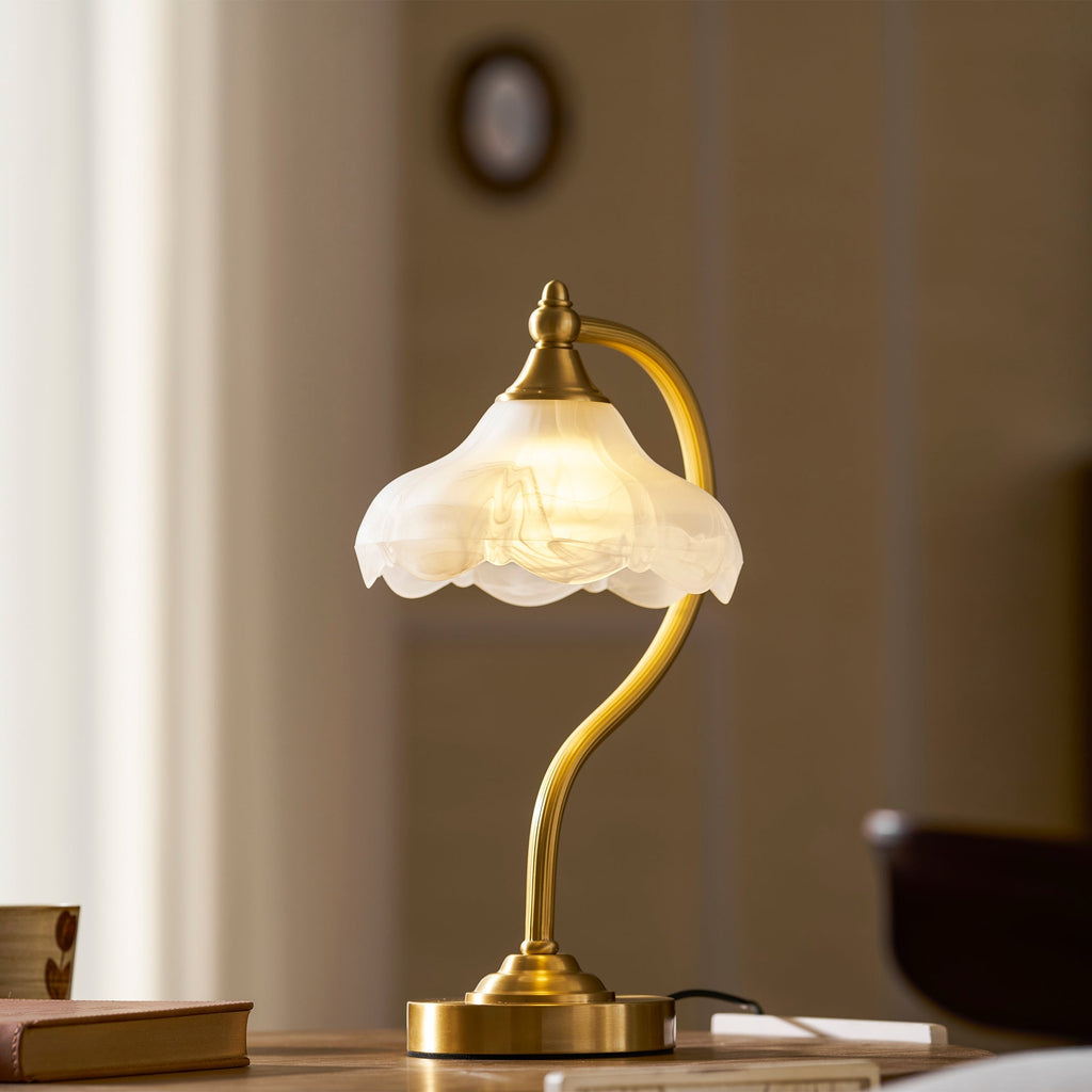 This Clérachic lamp glowing on a wooden table against a warm brown wall, its frosted shade lit softly from within.