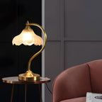 Against a dark grey wall, this Clérachic lamp stands on a small round side table next to a dusky-pink armchair.