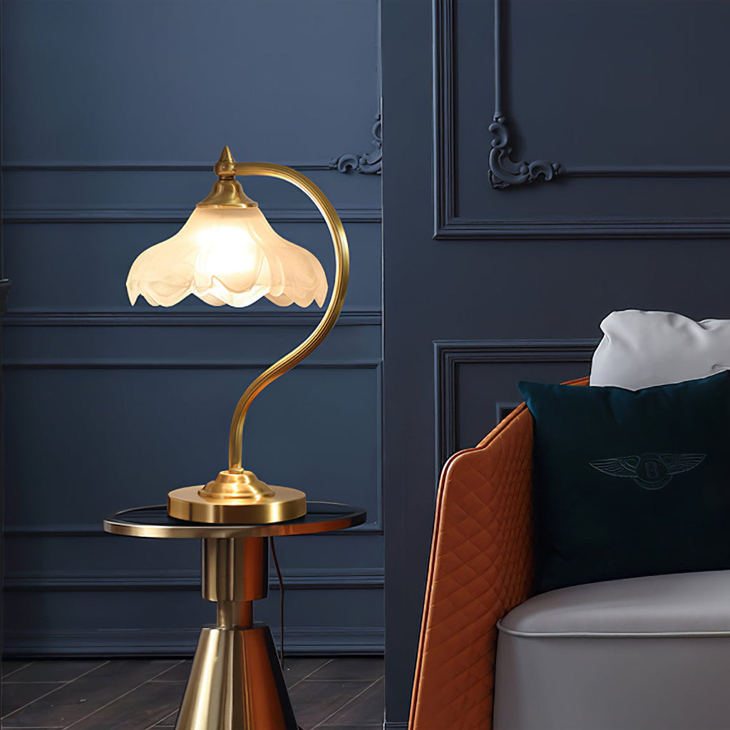 A lit Clérachic lamp on a gold-and-glass side table against a navy panelled wall, next to a tan leather armchair.