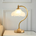 Wider view of this Clérachic lamp on a white cabinet, the scalloped shade glowing in front of a white panelled wall.