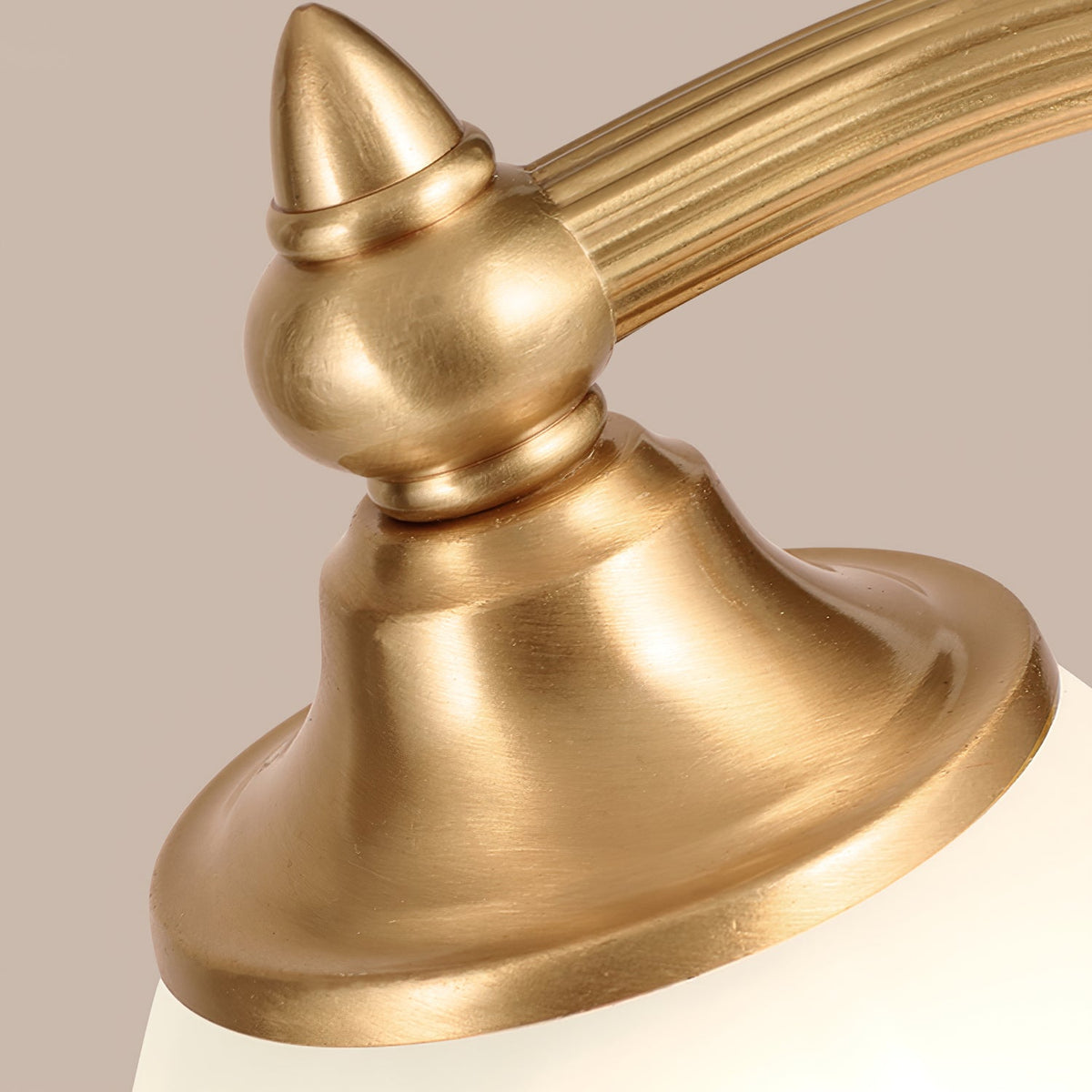 Close view of the brass finial, the reeded arm and the shade holder on this Clérachic lamp, with the frosted glass below.