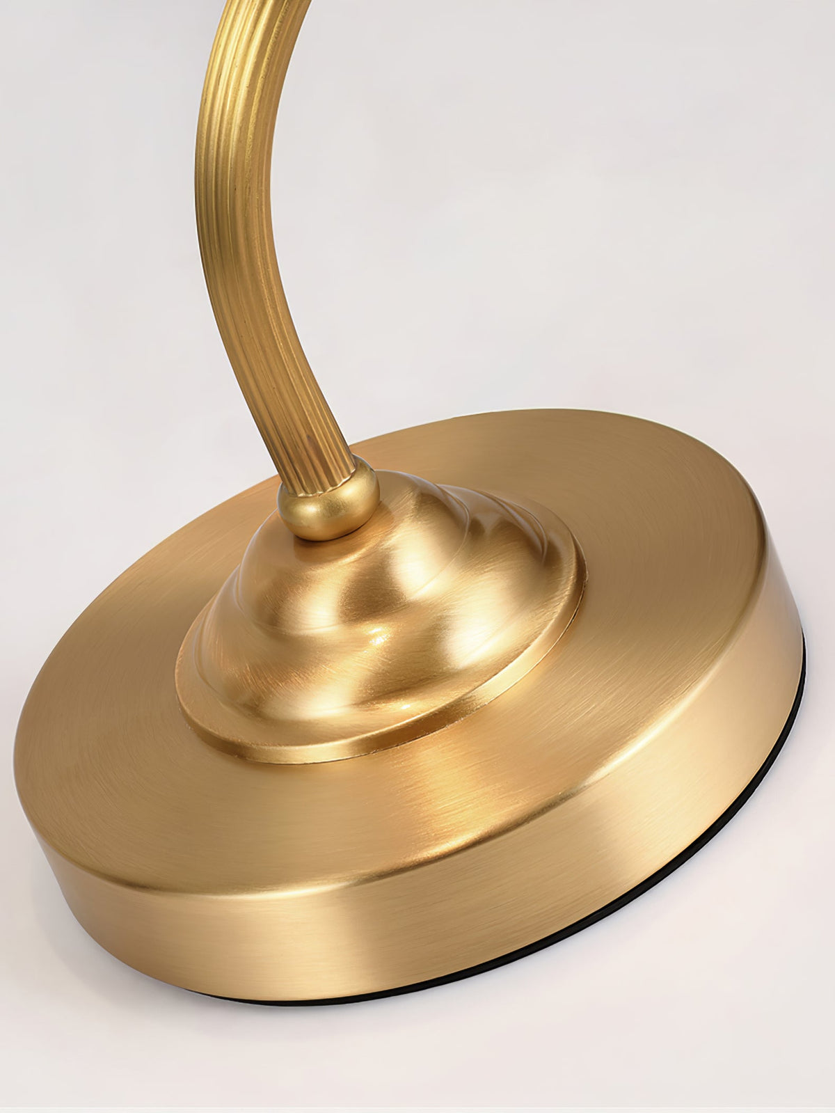 Close view of the stepped round base and the reeded brass arm where it meets the base on this Clérachic lamp.