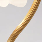 Close view of the fluted, ribbed texture along the curved brass arm of this Clérachic lamp, with the shade at the top.