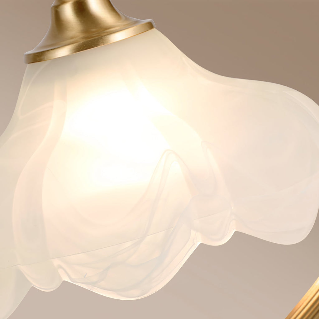 Close view of the lit frosted glass, with its soft petal-like folds, and the brass shade holder on this Clérachic lamp.