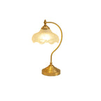 A smaller view of this Clérachic lamp lit on a white backdrop, the warm glass shade above a tall curved brass arm.