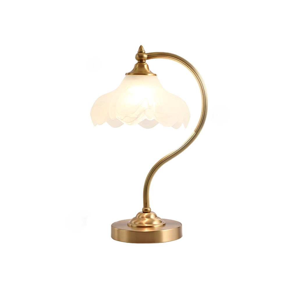 This Clérachic lamp softly lit on white, with its frosted shade glowing and a wide round brass base below.