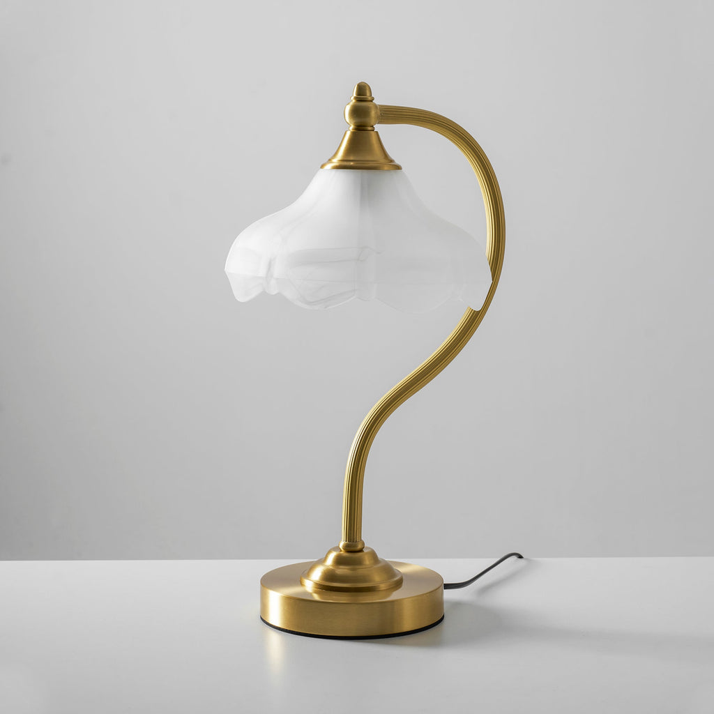 This Clérachic lamp unlit on a white table against a grey wall, with a black cord curling out from the base.
