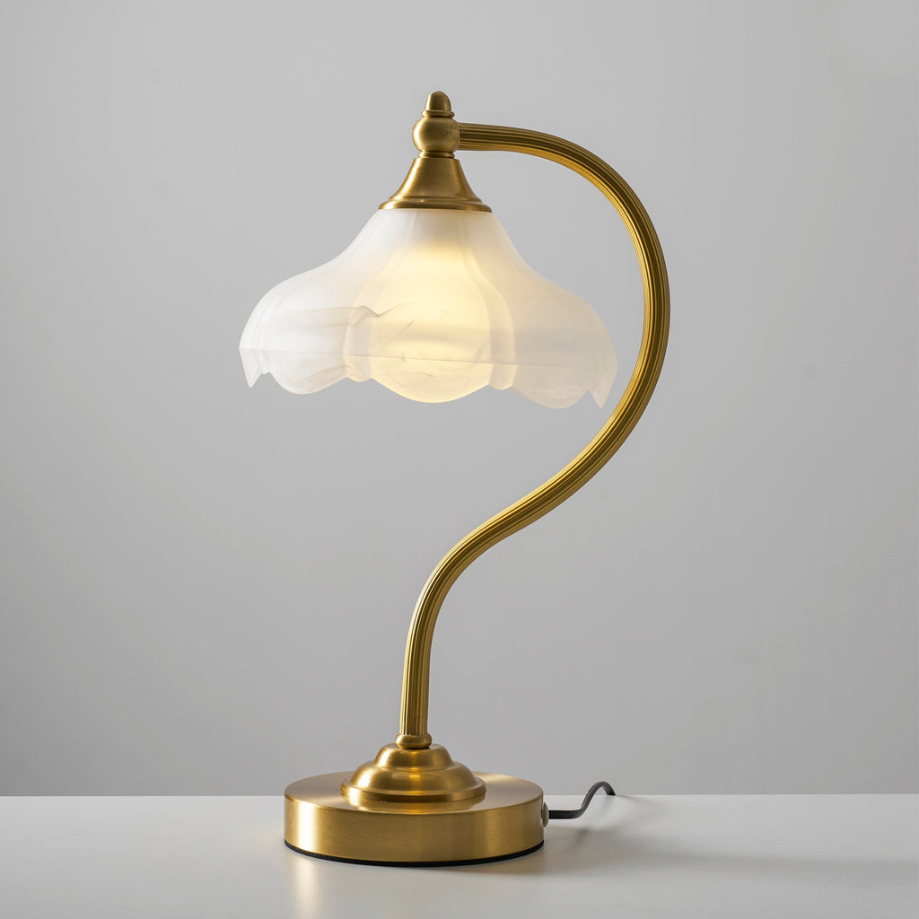 Straight-on view of this Clérachic lamp lit on a white tabletop, the warm light filling its frosted glass shade.