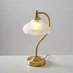 Angled view of this Clérachic lamp lit on a white table, with the cord running off to the right of the gold base.