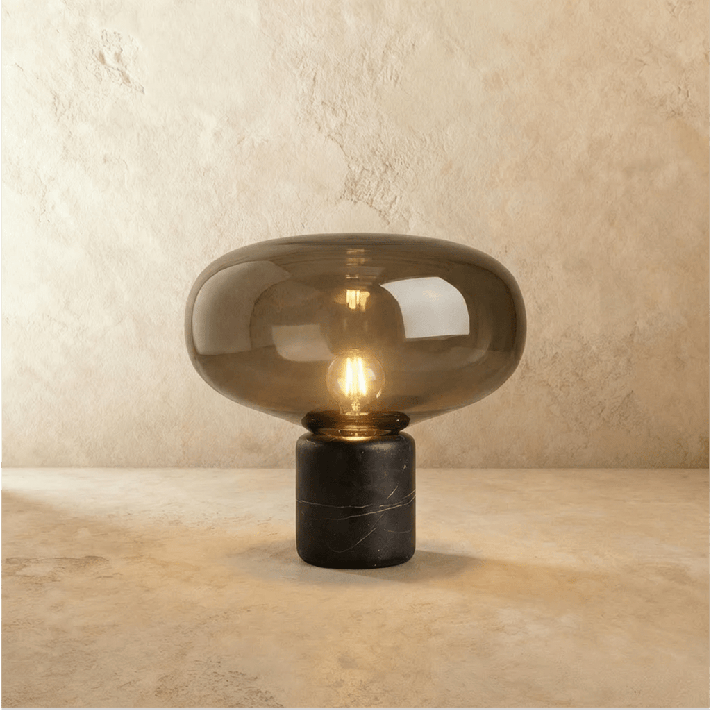 Clérachic larger table lamp with a broad tinted glass shade glowing warm above a black veined marble base