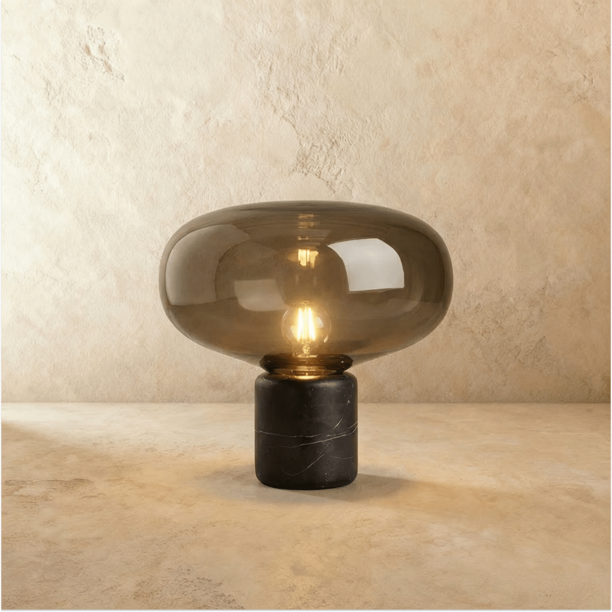 Clérachic larger table lamp with a broad tinted glass shade glowing warm above a black veined marble base