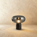 Clérachic table lamp with a mirrored smoky grey glass shade and an opal bulb above a black marble base
