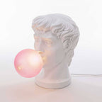 Close view of the carved curls and the frosted pink bubble on this Clérachic bust lamp, with its cord out to the right.
