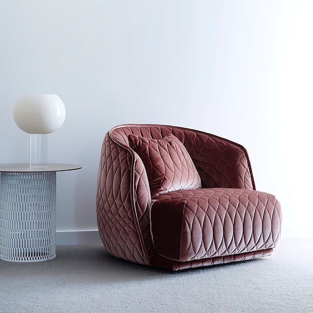A white globe Clérachic table lamp on a clear stem sits on a round side table beside a pink quilted velvet armchair.
