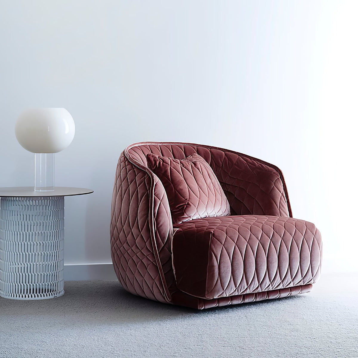 A white globe Clérachic table lamp on a clear stem sits on a round side table beside a pink quilted velvet armchair.
