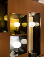 Several globe lamps glow in lit cut-outs of a rust-coloured display cabinet, in a shop setting for this Clérachic lamp style.