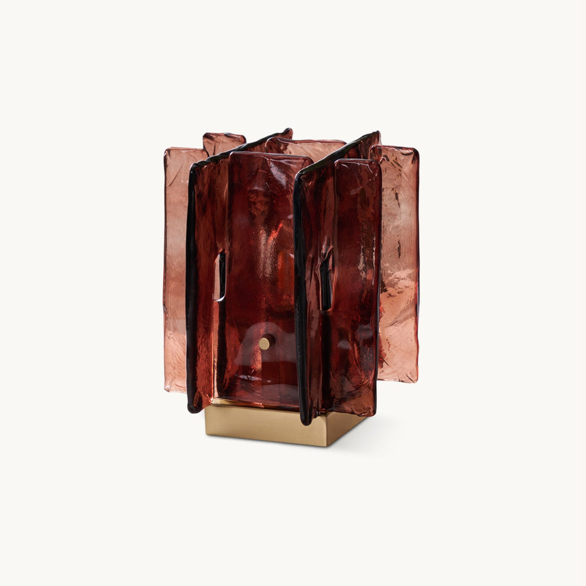 On a plain white backdrop, a Clérachic table lamp with rippled amber-red glass panels standing around a square brushed brass base.
