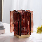 Unlit, this Clérachic table lamp shows its translucent amber-red glass panels and brass base on a marble table, with yellow flowers beside it.