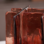 Close view of the hand-poured texture and dark-edged seams of the amber-red glass panels on this Clérachic table lamp.