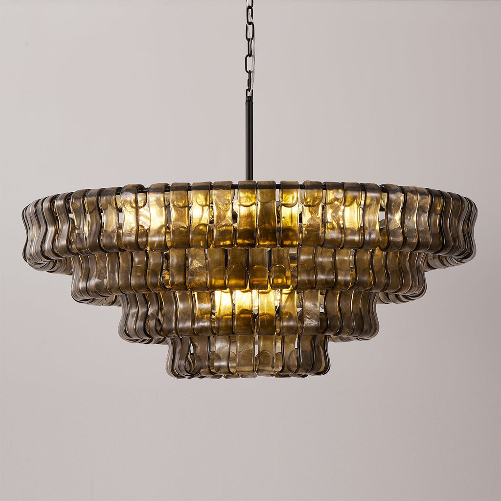 The smoke-grey glass tiers of this Clérachic chandelier hang on a black chain, glowing warm at the centre against pale grey.