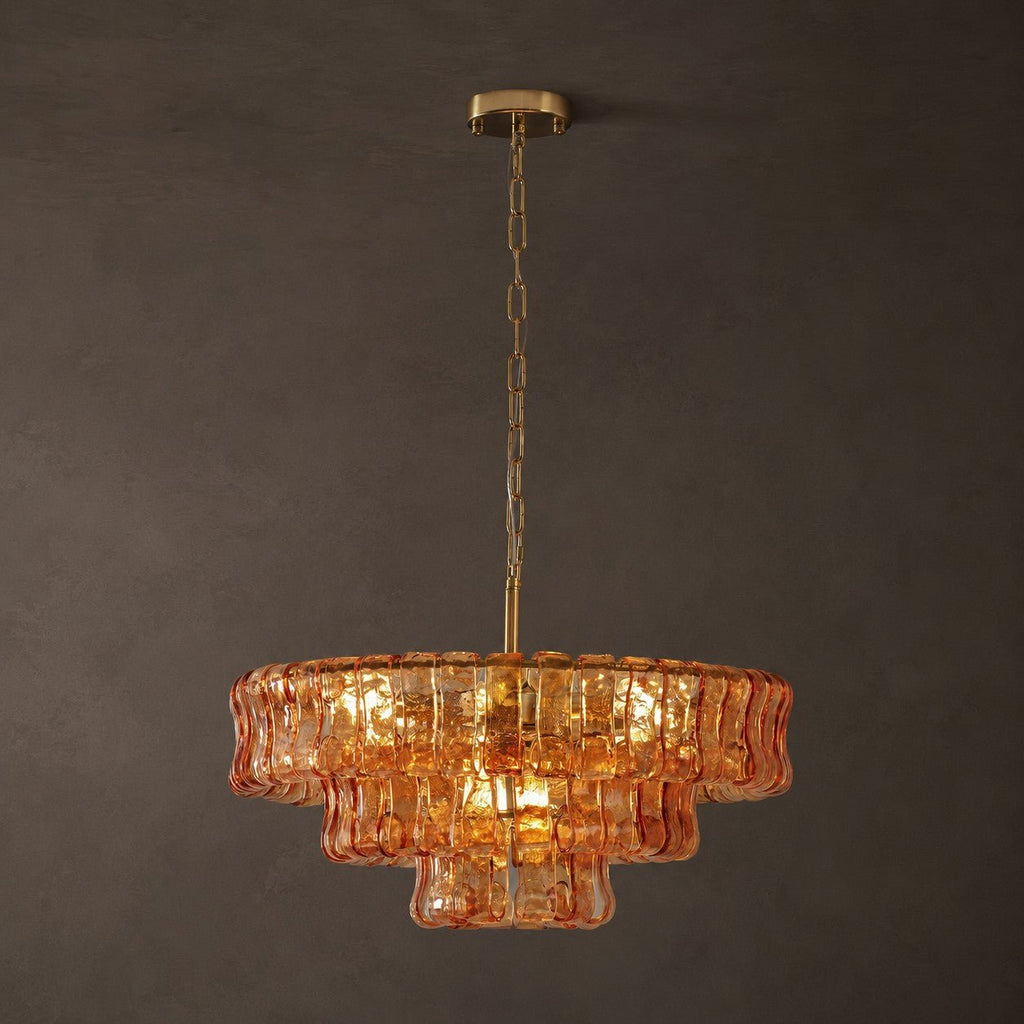 Lit amber glass on a Clérachic chandelier hanging from a brass chain and round canopy, in front of a charcoal wall.